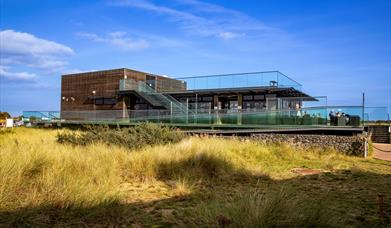 A viewing platform and cafe surrounded by sand dunes.