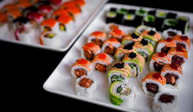 A plate of various sushi rolls on a white plate.