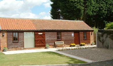 The exterior of a cottage with a small lawn and gravel driveway.